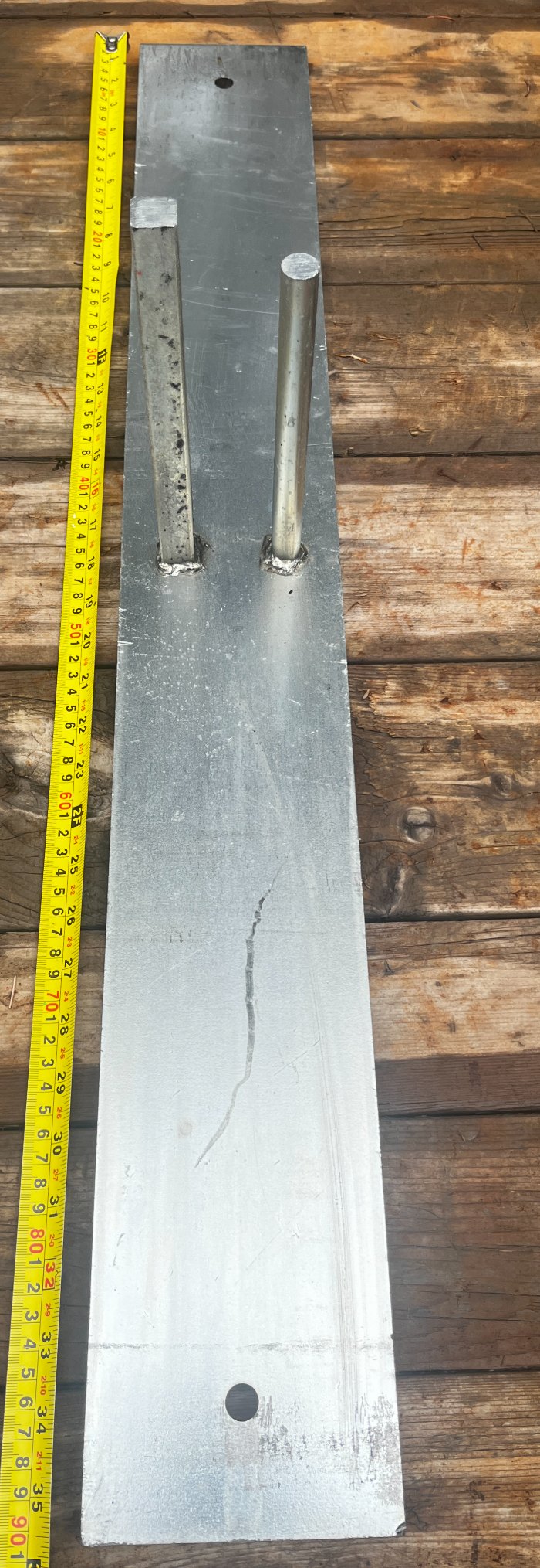 Tape measure alongside a StructSure base connector showing a 36 inch plate with two solid welded pegs