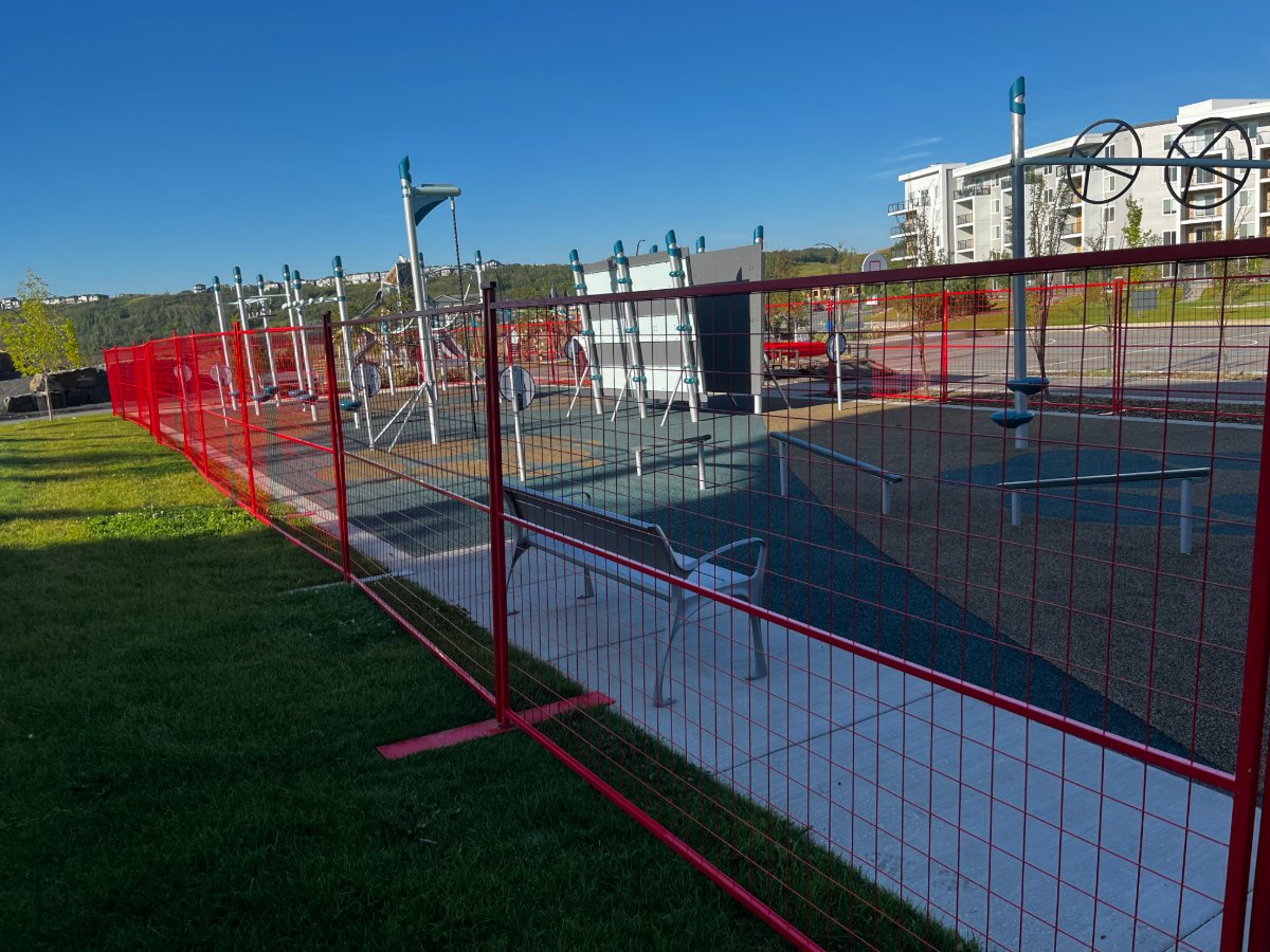 Red temporary fence enclosing a new playground build