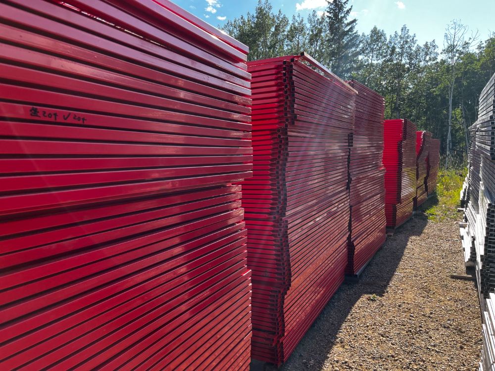 Rows of red temporary fence panels bundled on pallets in the StructSure yard