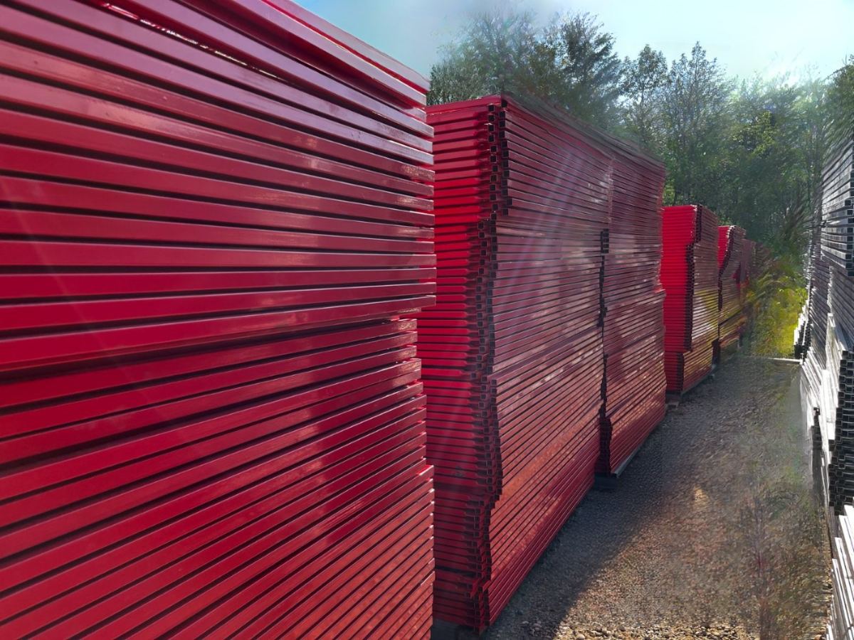 Long rows of red powder coated temporary fence panels stacked in the yard